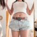 One Teaspoon denim shorts styled with a white crop top and heart belt, a top designer denim recommendation for achieving a trendy sweet yet edgy aesthetic.