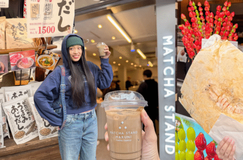 築地市場隱藏版美食地圖：Hattie 在 Matcha Stand Maruni 手拿培茶拿鐵，左側是築地限定飛魚高湯包攤位，右側則是比臉還大的現壓鮮蝦仙貝，展示除了海鮮丼以外的築地必吃必買推薦。
