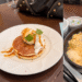 Blog banner collage featuring Denny's Japan restaurant entrance logo, classic caramel pancakes, and a hot bowl of shrimp chicken soup rice.