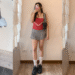 A three-photo collage showcasing different ways to style an I.AM.GIA grey pleated mini skirt for a petite look, including Y2K preppy style with pink slouch socks, a red lace cami top, and a sporty Blokette outfit.