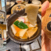 Collage showing Godaime Hanayama Udon Ginza storefront, signature Oni Himokawa wide udon in a tanuki bowl, and a cute ceramic tanuki cup.